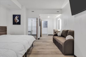 Una habitación de hotel moderna con cama, sofá, escritorio y un espejo grande.