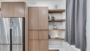 A kitchen with wooden cabinets, a stainless steel refrigerator, and a built-in shelf with decorative items. - Downtown Indy-Entire Building-77 Guests (Indianapolis)