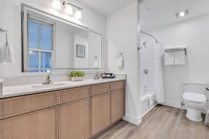 Un baño moderno con un espejo grande, armarios de madera, ducha y retrete.