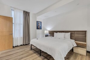 A hotel room with a bed, bedside table, lamp, and a wooden wardrobe.