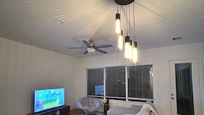 A living room with a flat-screen TV, a ceiling fan, and pendant lights. - Conveniently located Spacious Houston Heights Home-King Suite-Sleeps 6 (Houston)