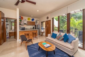 Ein modernes Wohnzimmer mit einer Couch, einem Couchtisch und Blick ins Freie.