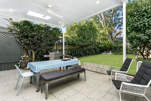 Eine Terrasse im Freien mit Tisch, Stühlen und Grill.