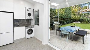 Una cucina moderna con lavatrice, forno integrato e zona pranzo con tavolo e sedie.