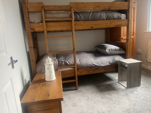 A bunk bed with a ladder, a bedside table, and a nightstand.