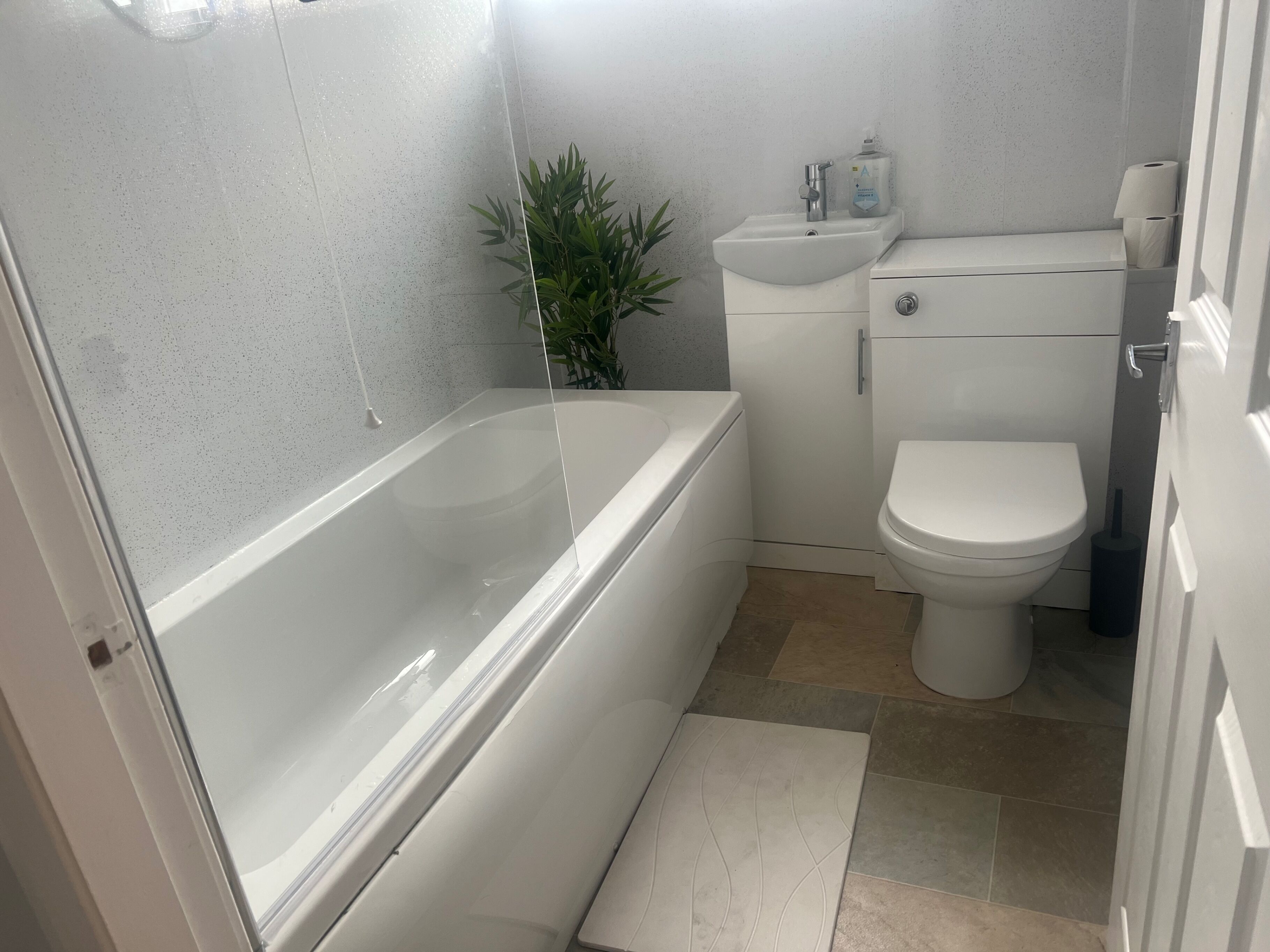 Une salle de bain avec une baignoire, des toilettes, un lavabo et une plante en pot.