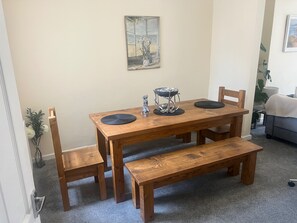 A wooden dining table with a bench, a painting on the wall, and a plant in the corner. - Central Sutton on Sea 4-bed House, Sleeps 8 (Mablethorpe)