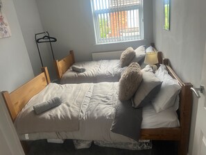 A room with two wooden beds, a radiator, a lamp, and a window with bars. - Central Sutton on Sea 4-bed House, Sleeps 8 (Mablethorpe)