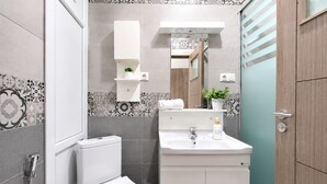 Et moderne badeværelse med toilet, håndvask og brusebad.