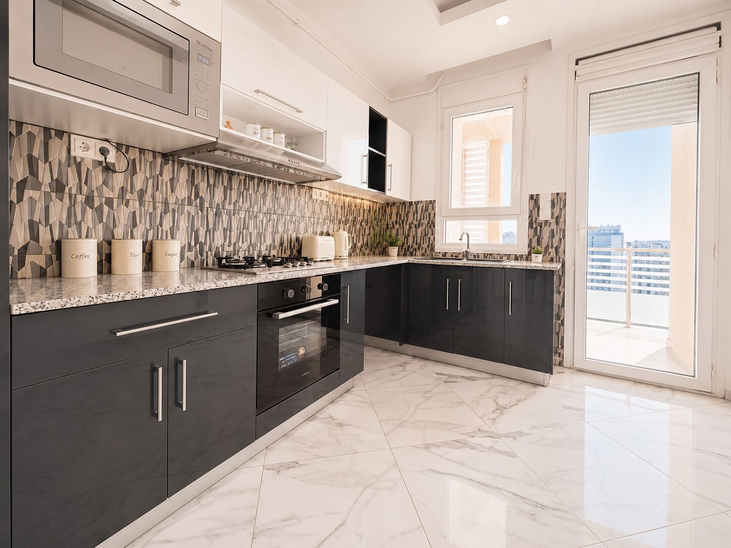 A modern kitchen with dark cabinets, a marble countertop, and a view of the city.