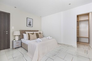 A bedroom with a bed, bedside tables, a lamp, a framed picture, and a wooden wardrobe. - Magnifique Appartement a Constantine (Constantine)
