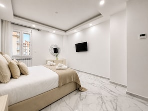 Un dormitorio moderno con una cama, un televisor y una ventana que ofrece vistas a edificios.