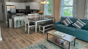 Une cuisine moderne avec des meubles blancs, un réfrigérateur en acier inoxydable et un coin repas comprenant une table et des chaises.