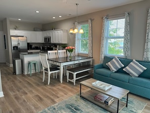A modern kitchen with white cabinets, a stainless steel refrigerator, and a dining area with a table and chairs. - Whole Townhouse with Ocean View and only a 2-minute walk to the Beach! (Myrtle Beach)