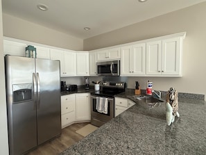 A modern kitchen with white cabinets, stainless steel appliances, granite countertops, and a built-in oven. - Whole Townhouse with Ocean View and only a 2-minute walk to the Beach! (Myrtle Beach)