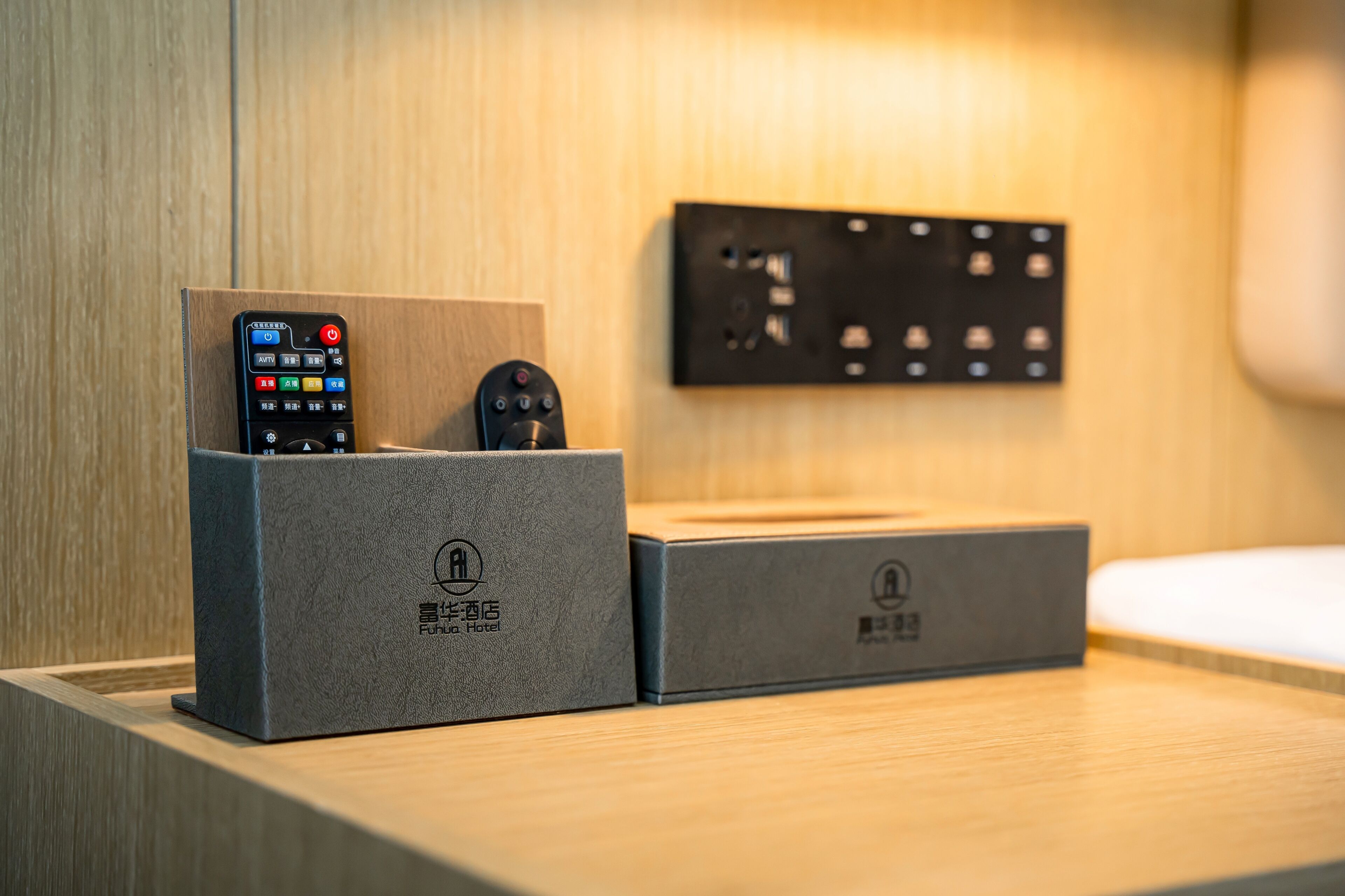 Deux boîtiers gris équipés de télécommandes, un panneau de commande fixé au mur et une surface en bois.