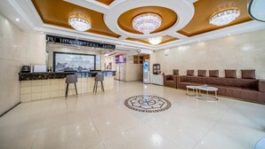 A hotel lobby with a reception desk, bar area, seating, and a decorative floor pattern. - Fu Hua Jun Yue Hotel (Luntai County)