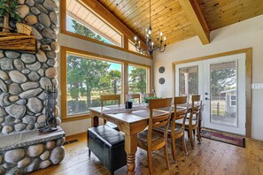 Un espace repas avec un mur en pierre, un plafond en bois et de grandes fenĂȘtres.
