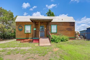 A log cabin with a porch, a front door, and a small staircase leading up to the entrance.