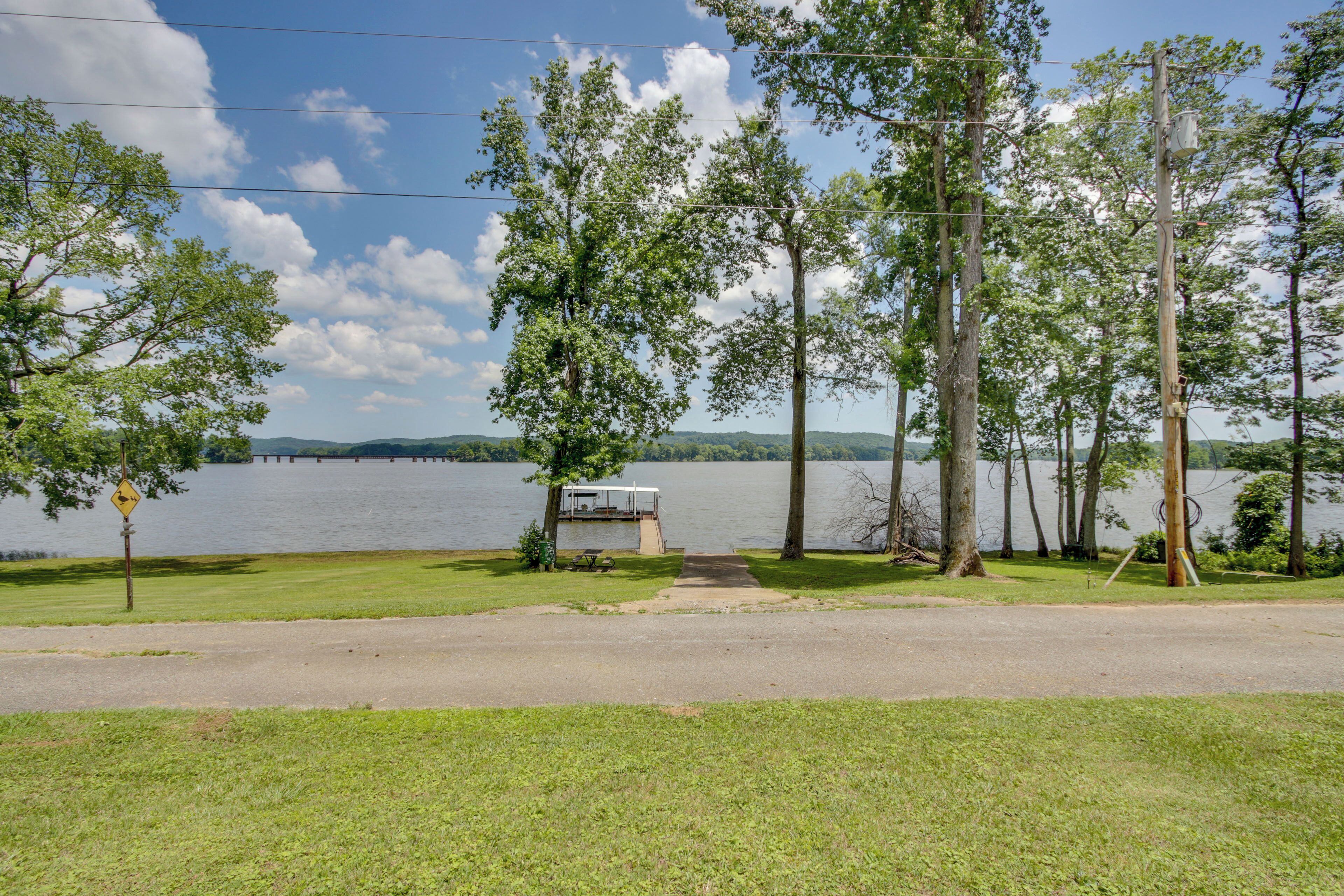 A lakeside view with a dock, grassy area, and trees.