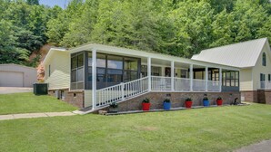 A two-story house with a covered porch, a brick foundation, and a grassy yard.