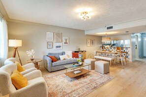 Ein Wohnzimmer mit Sofa, Sesseln, einem Couchtisch und einem Essbereich mit Tisch und Stühlen.