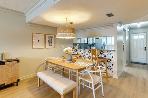 Ein Essbereich mit Holztisch, weißen Stühlen, einer Bank und einer Pendelleuchte.