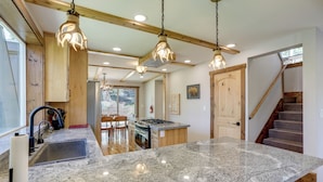 A kitchen with granite countertops, wooden cabinets, and pendant lighting. - Hike, Ski & Explore! Spacious Home in Twin Bridges (Echo Lake)