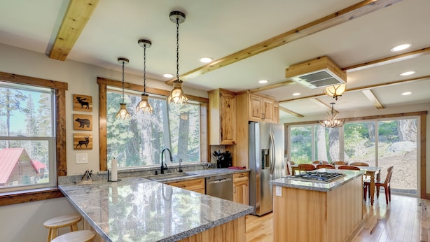 A spacious kitchen with wooden cabinets, granite countertops, and a central island with stools. - Hike, Ski & Explore! Spacious Home in Twin Bridges (Echo Lake)