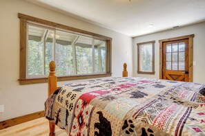 A bedroom with a large window, a wooden bed, and a door.