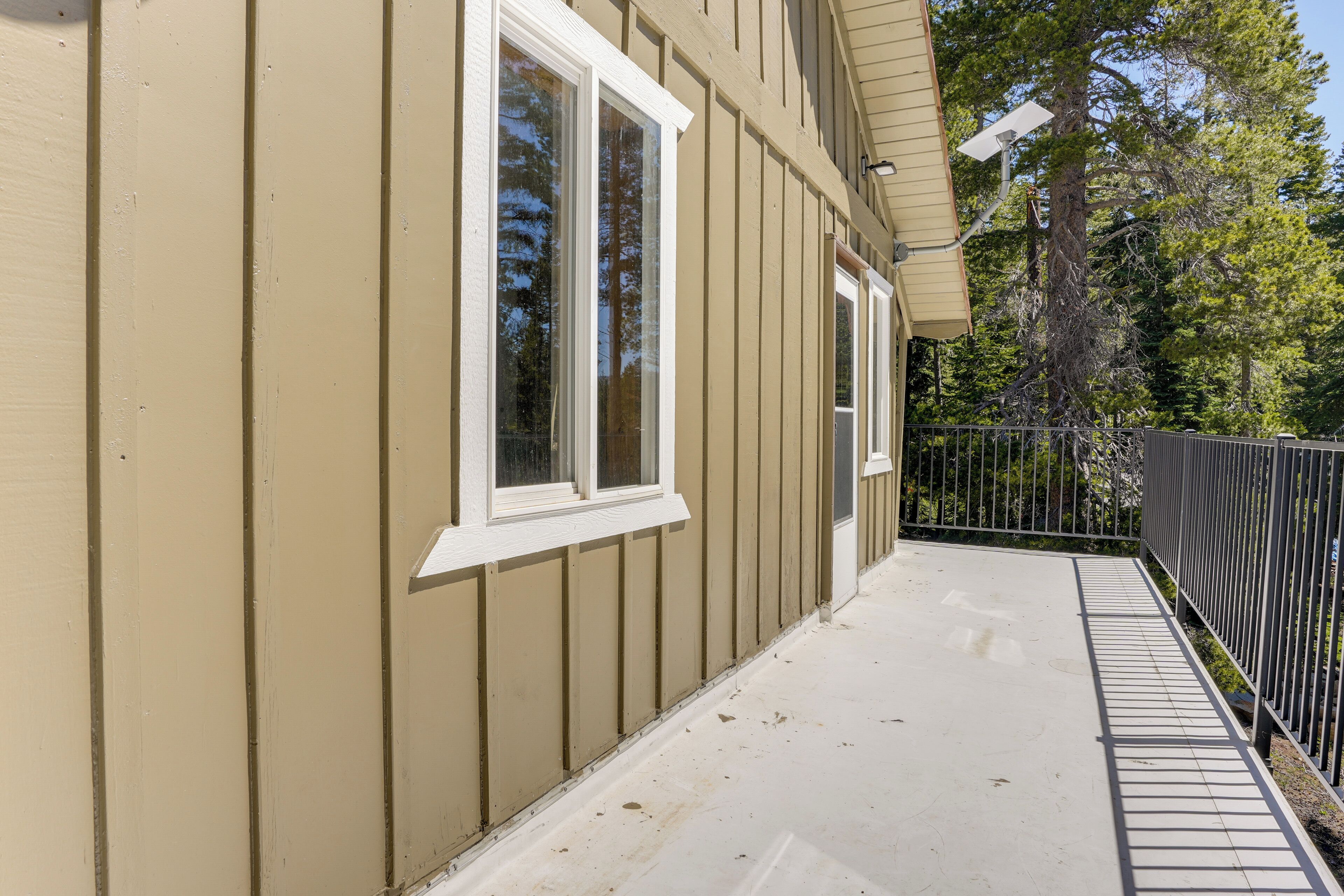 A building with beige siding, white trim around windows, a covered porch, and a black metal fence.