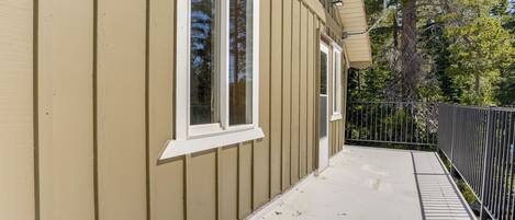 A building with beige siding, white trim around windows, a covered porch, and a black metal fence.