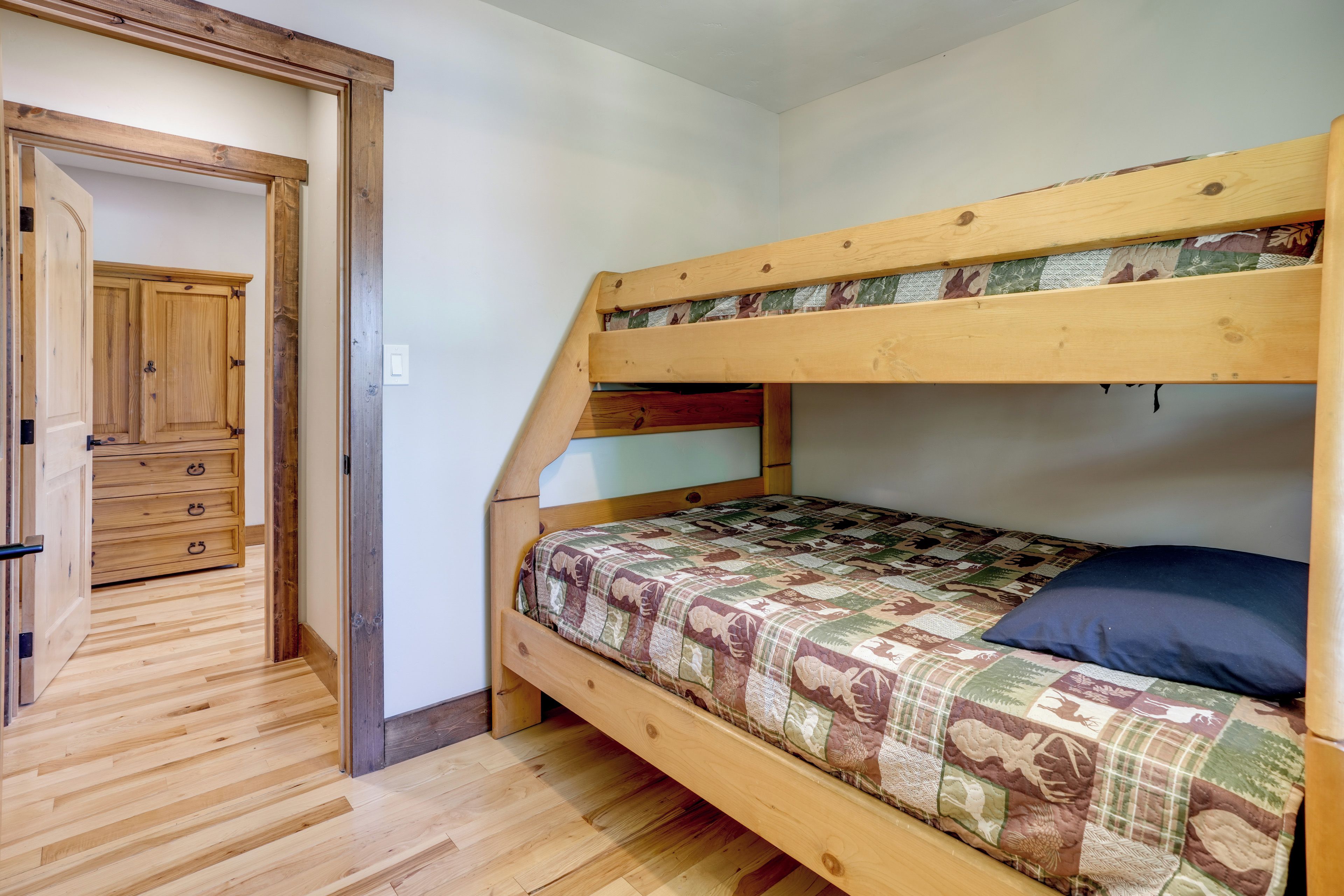 Un lit superposé avec une couvre-lit matelassé, une armoire en bois et un plancher en bois.