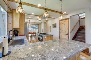 A kitchen with granite countertops, wooden cabinets, and pendant lighting.