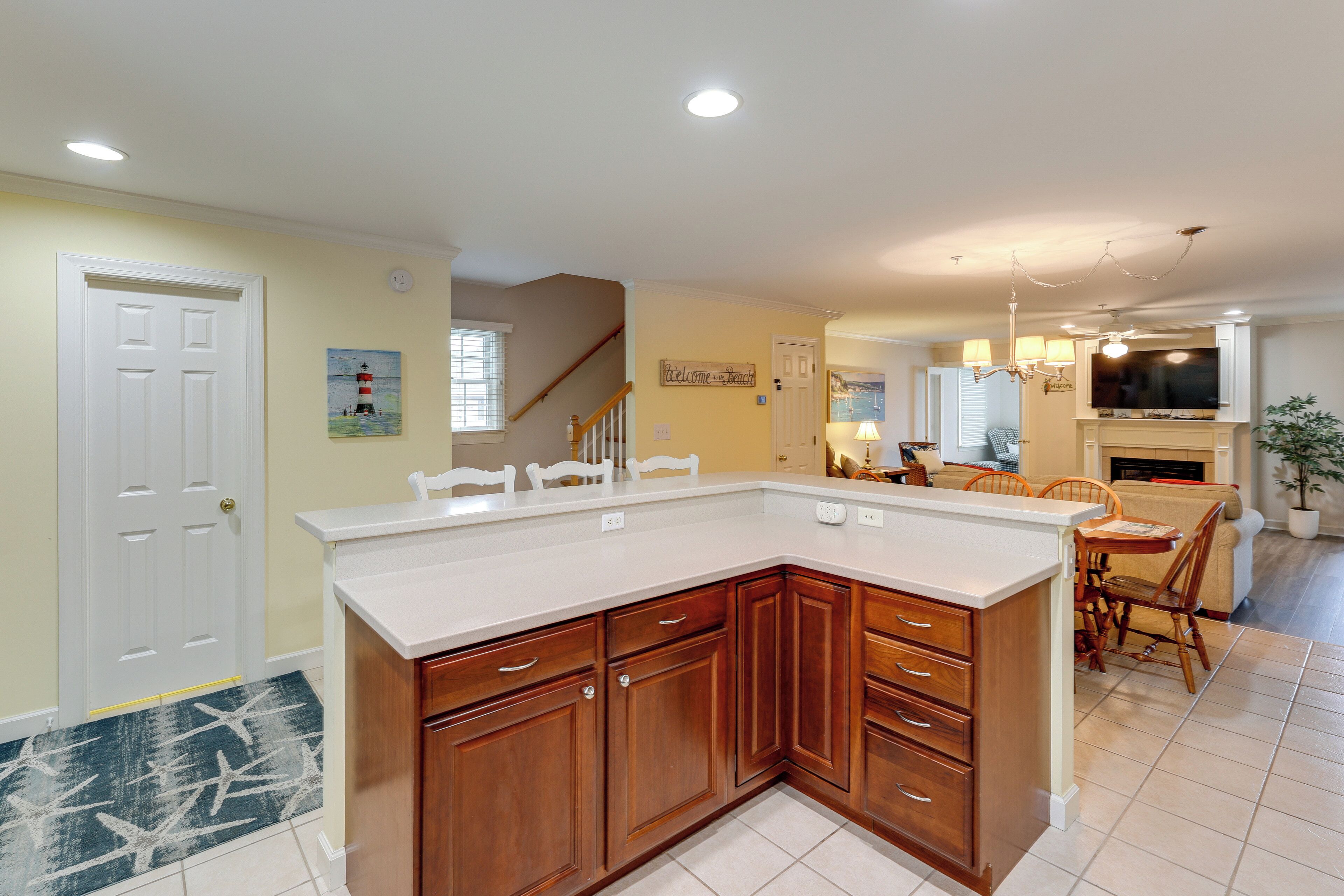 A kitchen with wooden cabinets, a white countertop, and a dining area with a table and chairs.