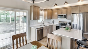 A modern kitchen with wooden cabinets, stainless steel appliances, and a large island. - Boat & Fish on Cow Creek! Brand-new Pierre Home (Pierre)