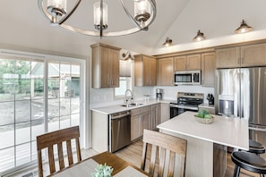 A modern kitchen with wooden cabinets, stainless steel appliances, and a large island.