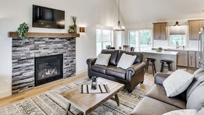 A living room with a fireplace, leather sofa, and a coffee table. - Boat & Fish on Cow Creek! Brand-new Pierre Home (Pierre)