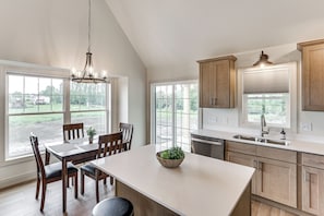 A kitchen with a large island, wooden cabinets, and a view of the outdoors.