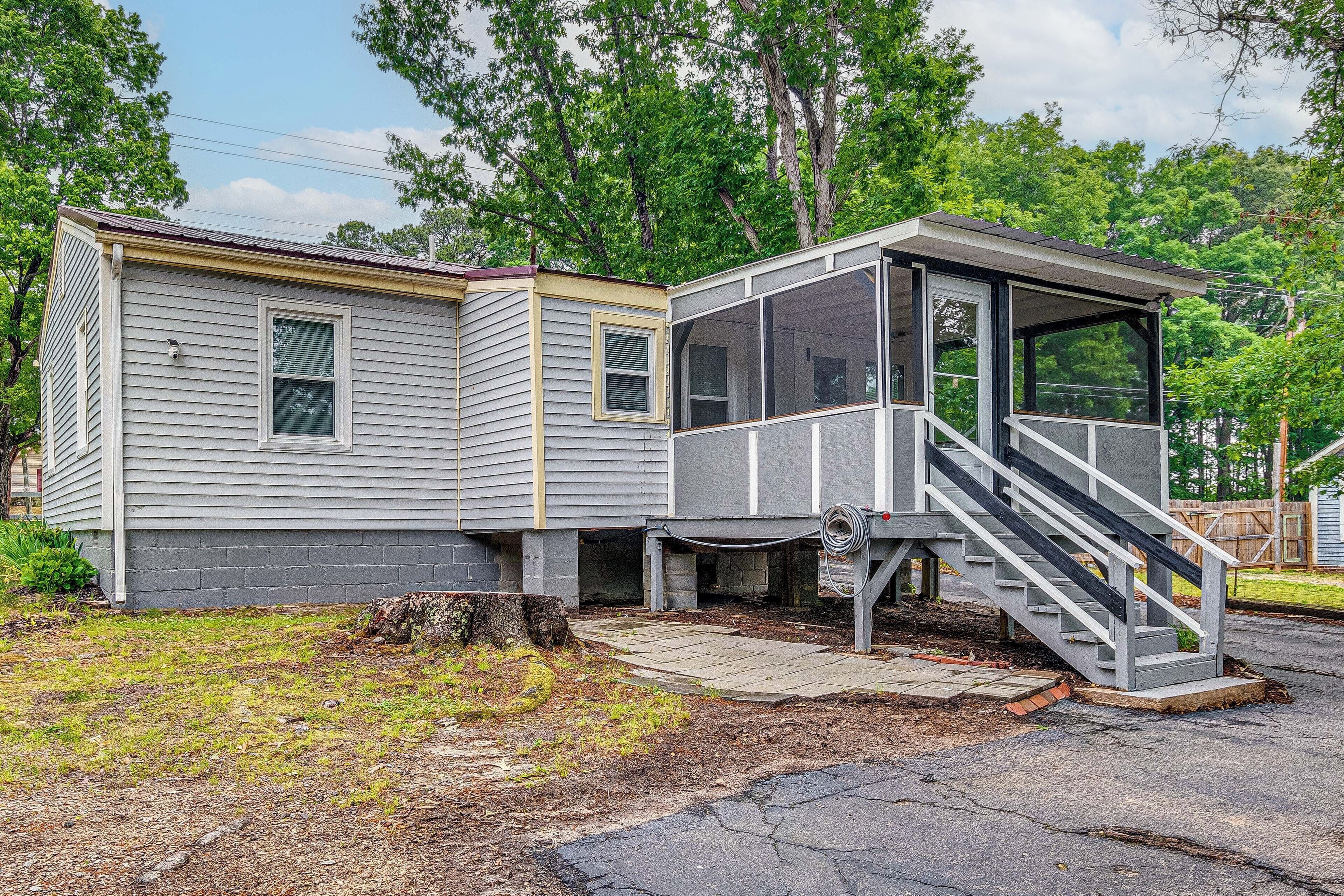 A mobile home with a porch and a staircase leading to a covered area.