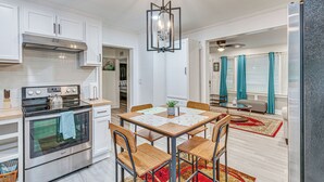 Une cuisine moderne avec des meubles blancs, une cuisinière en acier inoxydable et un coin repas comprenant une table et des chaises.