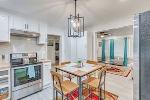 A modern kitchen with white cabinetry, a stainless steel stove, and a dining area with a table and chairs. - Pet Friendly + Peaceful: Family Home Near Main St! (Franklinton)