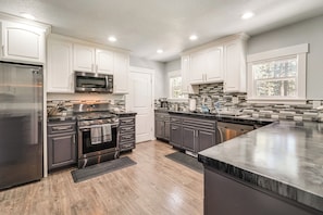 A modern kitchen with white cabinets, stainless steel appliances, and a large island.