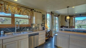 A kitchen with a dishwasher, a sink, and a window with a view of the mountains.