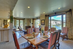 Un comedor con mesa de madera, sillas a cuadros y vistas a un lago.