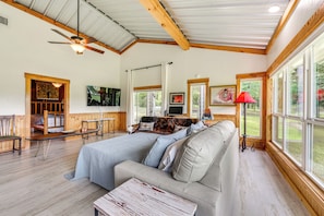 A cozy room with a large bed, a sofa, a wooden table, and a ceiling fan.