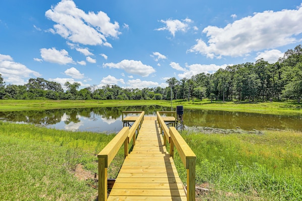 A wooden deck leading to a body of water with trees in the background.