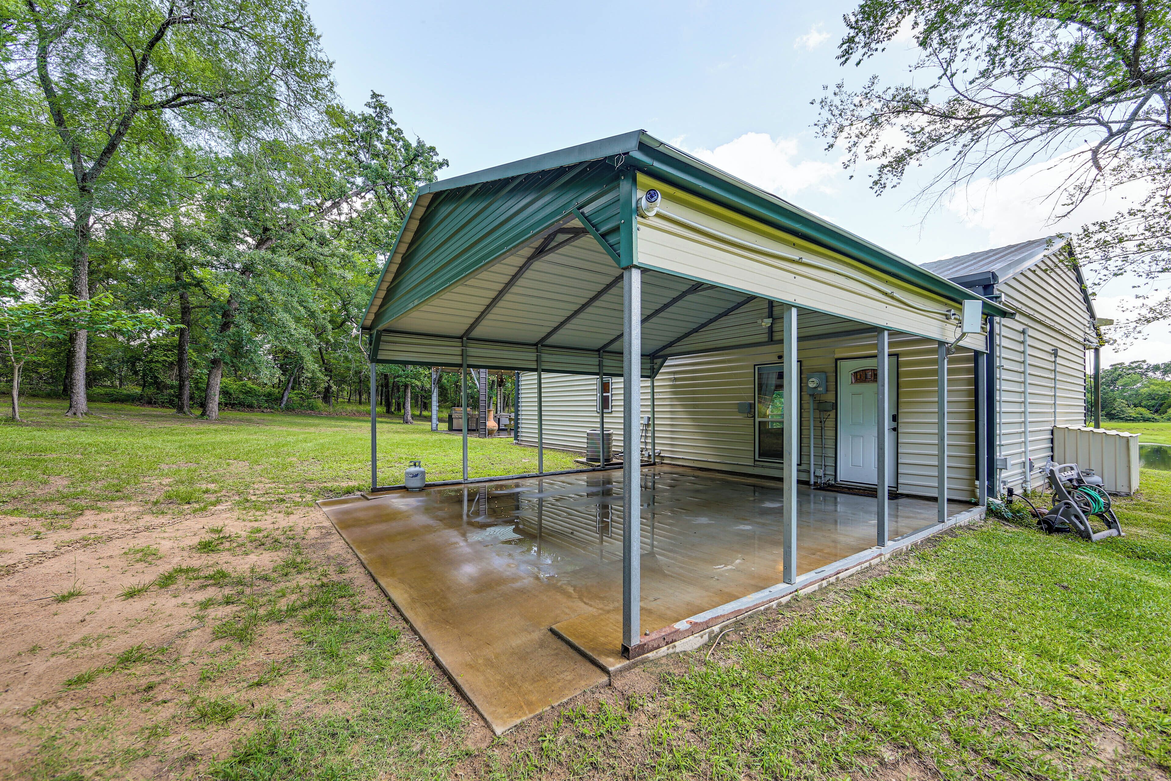 A covered outdoor area with a metal roof, a concrete floor, and a lawn.