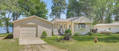 A single-story house with a garage, a covered porch, and a small front yard with a tree stump and a fire hydrant.