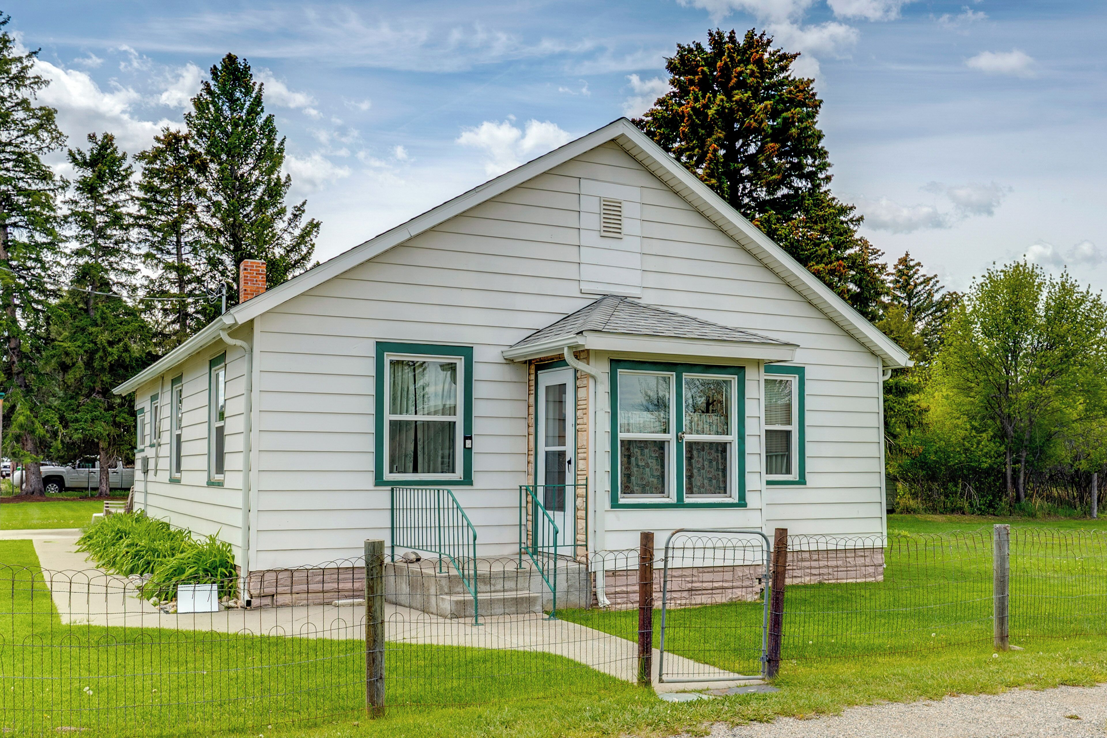 A single-story house with a front porch, a small front yard, and a fenced property.